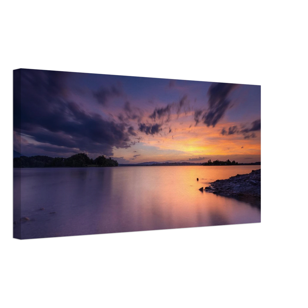 „Leinwandbild eines spektakulären Sonnenuntergangs am Staffelsee in Seehausen, Oberbayern. Farbenprächtiges Wolkenspiel in Gold-, Orange- und Violetttönen über dem ruhigen See an einem warmen Sommerabend mit stimmungsvollen Spiegelungen im Wasser.“