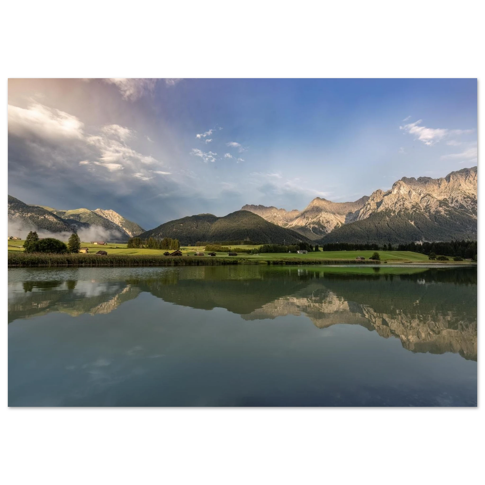 
Horizontales, ungerahmtes Poster mit Landschaftsmotiv: ruhiger Bergsee mit klarer Spiegelung, grüne Wiesen, kleine Hütten und das Karwendelgebirge im warmen Licht der goldenen Stunde unter einem dramatischen Himmel.
