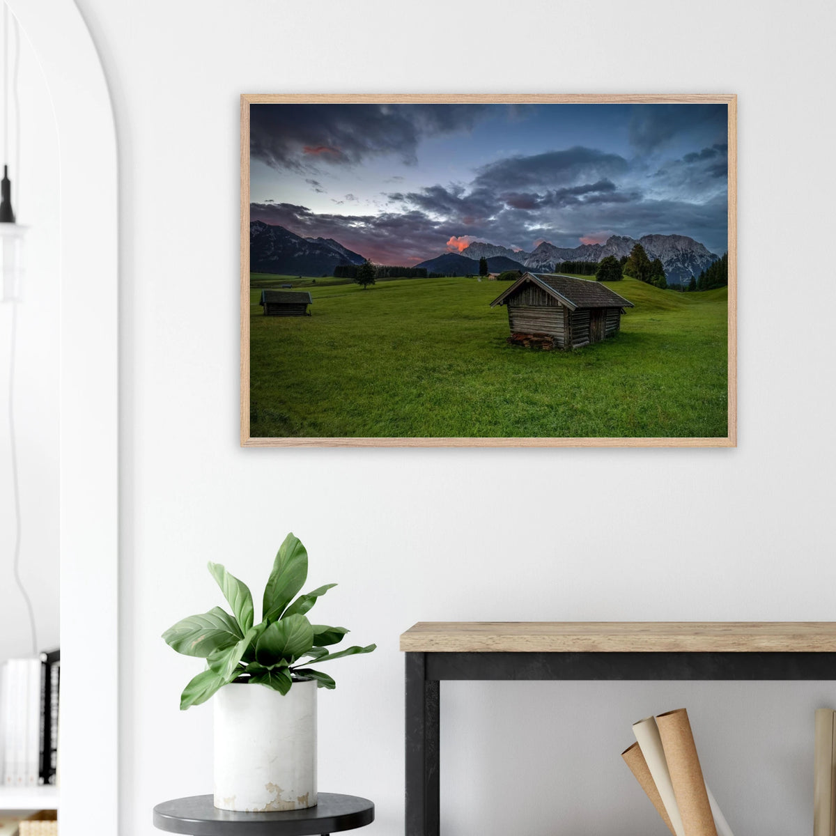 Grüne Buckelwiesen bei Krün mit traditionellen Heustadeln, dem Karwendelgebirge im Hintergrund und dramatischen Regenwolken in der frühen Morgenstimmung.
