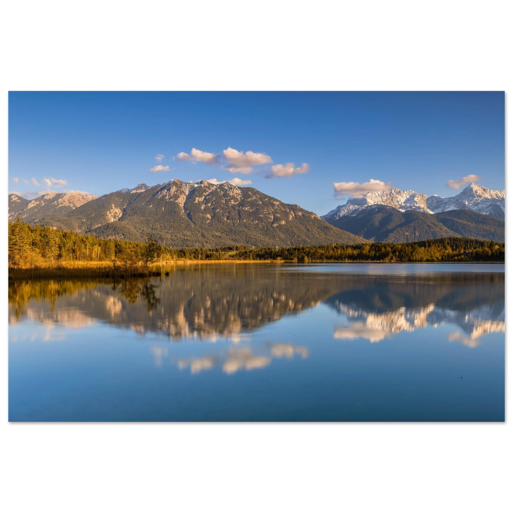 Stimmungsvolle Aufnahme des Barmsees in Oberbayern mit ruhiger Spiegelung der Berge im klaren Wasser, sanftem Abendlicht und weiter blauer Himmelkulisse.