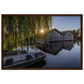 Gerahmtes Premium-Matt-Poster mit Bootshäusern in Seehausen am Staffelsee bei warmer Morgensonne, eingefasst in einen dunkelbraunen Holzrahmen.
