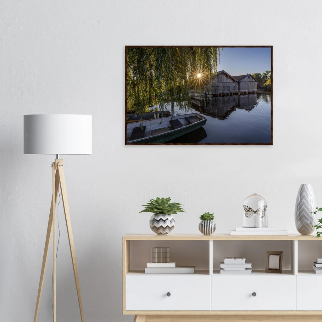 Gerahmtes Premium-Matt-Poster mit Bootshäusern in Seehausen am Staffelsee bei warmer Morgensonne, eingefasst in einen dunkelbraunen Holzrahmen.