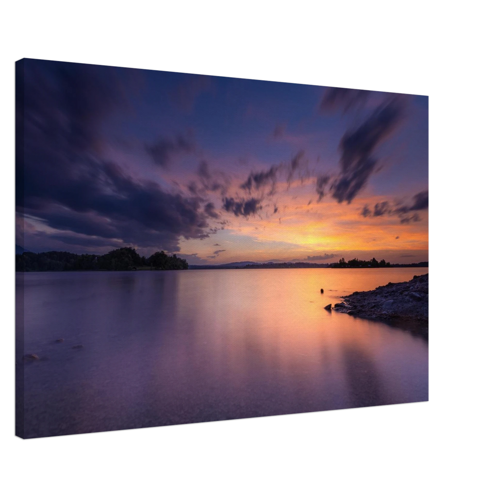 „Leinwandbild eines spektakulären Sonnenuntergangs am Staffelsee in Seehausen, Oberbayern. Farbenprächtiges Wolkenspiel in Gold-, Orange- und Violetttönen über dem ruhigen See an einem warmen Sommerabend mit stimmungsvollen Spiegelungen im Wasser.“