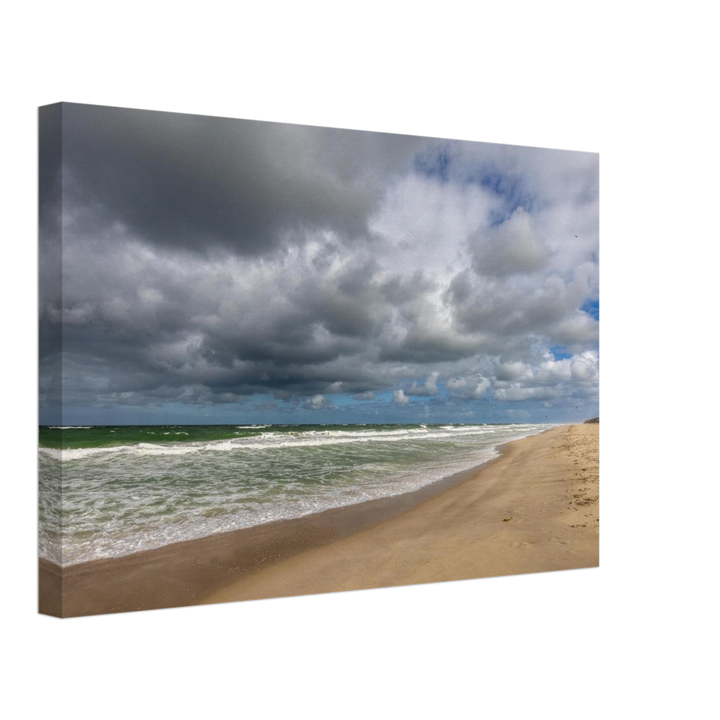 
Weite Strandlandschaft in Westerland auf Sylt mit kräftiger Nordseebrandung, aufgewühltem grünblauem Meer, feinem Sandstrand und eindrucksvollen dunklen Wolken unter aufbrechendem blauem Himmel.
