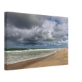 
Weite Strandlandschaft in Westerland auf Sylt mit kräftiger Nordseebrandung, aufgewühltem grünblauem Meer, feinem Sandstrand und eindrucksvollen dunklen Wolken unter aufbrechendem blauem Himmel.
