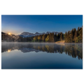 Ein stiller Morgen am Geroldsee in Oberbayern. Feine Nebelschleier ziehen sanft über das ruhige Wasser, während sich die umliegenden Wälder und die Bergwelt nahezu vollkommen im See spiegeln. Das erste warme Licht des Tages berührt die Bäume und schenkt der Landschaft eine besondere Ruhe und Tiefe.

