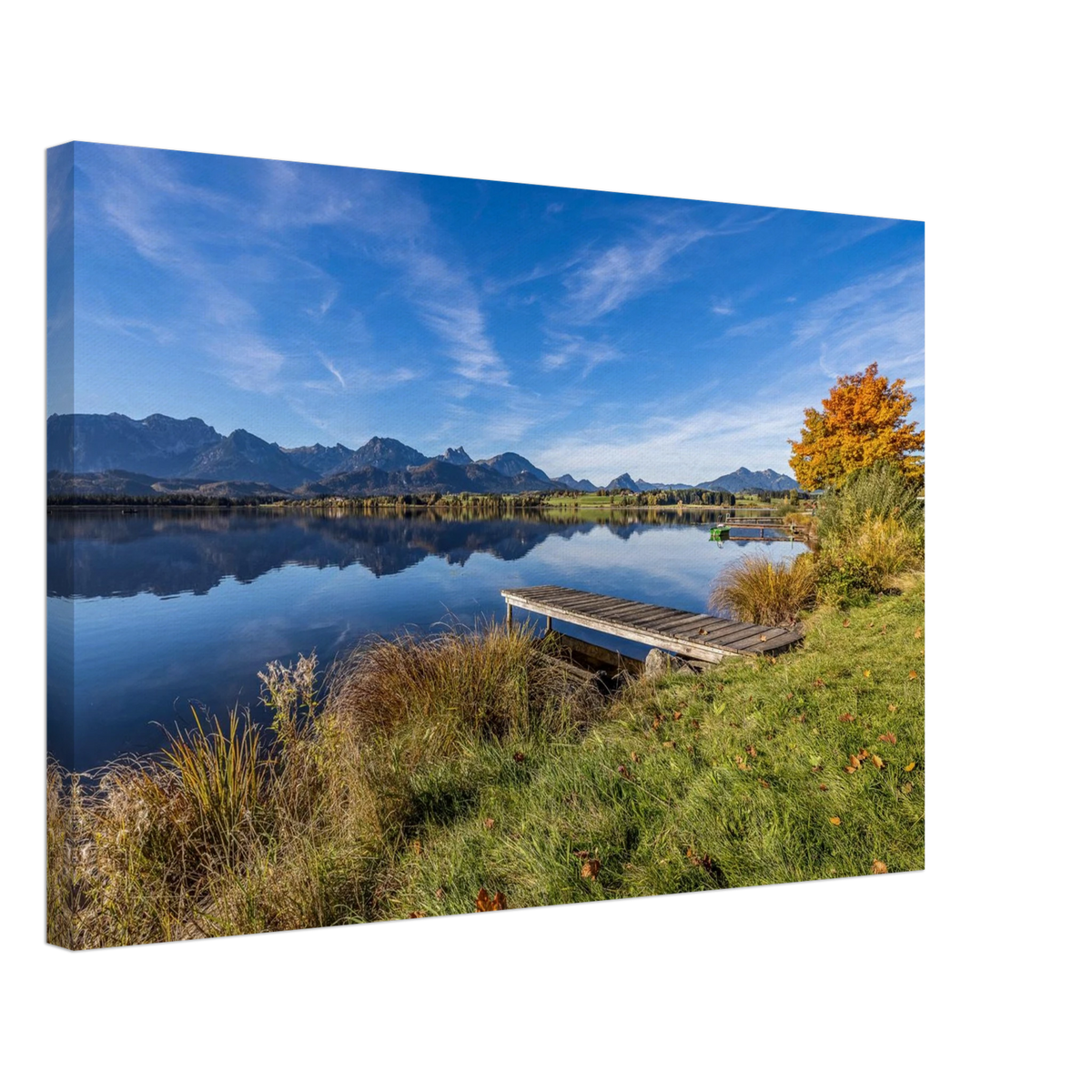 Ein goldener Herbsttag im Allgäu. Der Hopfensee liegt still vor der beeindruckenden Kulisse der Berge, das klare Wasser trägt ihre Spiegelungen und am Ufer leuchtet der Herbst in warmen Farben. Der kleine Holzsteg führt hinaus in diese besondere Ruhe, die man manchmal nur in der Natur findet.Leinwandbild