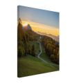 Leinwandbild mit 2 cm starkem Keilrahmen, Sonnenuntergang im Werdenfelserland. Ein geschwungener Weg führt durch herbstlich gefärbte Wälder hinauf nach Wamberg, dem höchstgelegenen Kirchdorf Deutschlands. Die kleine Kirche liegt eingebettet in die Landschaft, während die untergehende Sonne die Berggipfel und den Himmel in warmes goldenes Licht taucht.