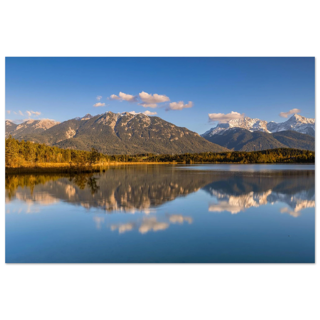 Stimmungsvolle Aufnahme des Barmsees in Oberbayern mit ruhiger Spiegelung der Berge im klaren Wasser, sanftem Abendlicht und weiter blauer Himmelkulisse.