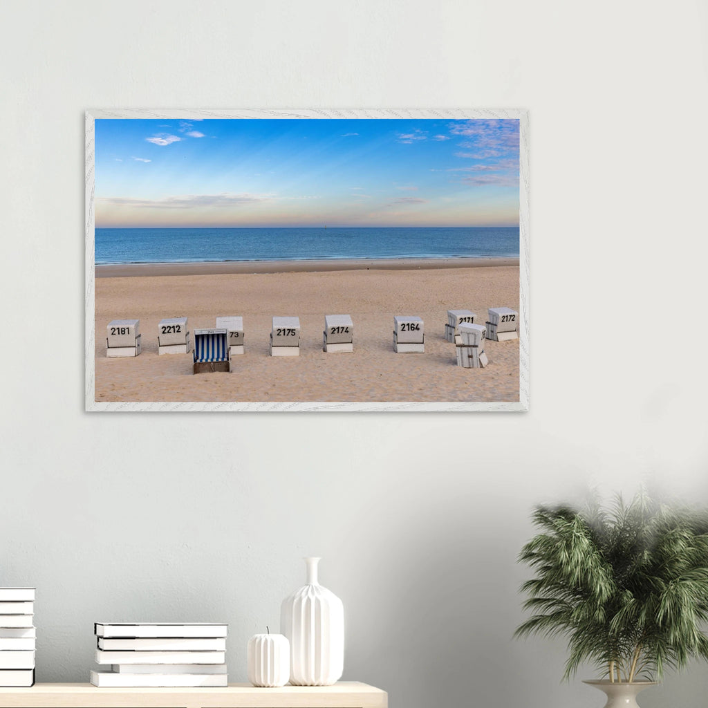 Horizontaler Kunstdruck mit Blick auf den Strand von Westerland auf Sylt: weiße Strandkörbe im hellen Sand, dahinter die ruhige blaue Nordsee und ein weiter sommerlicher Himmel mit feinen Wolken.
