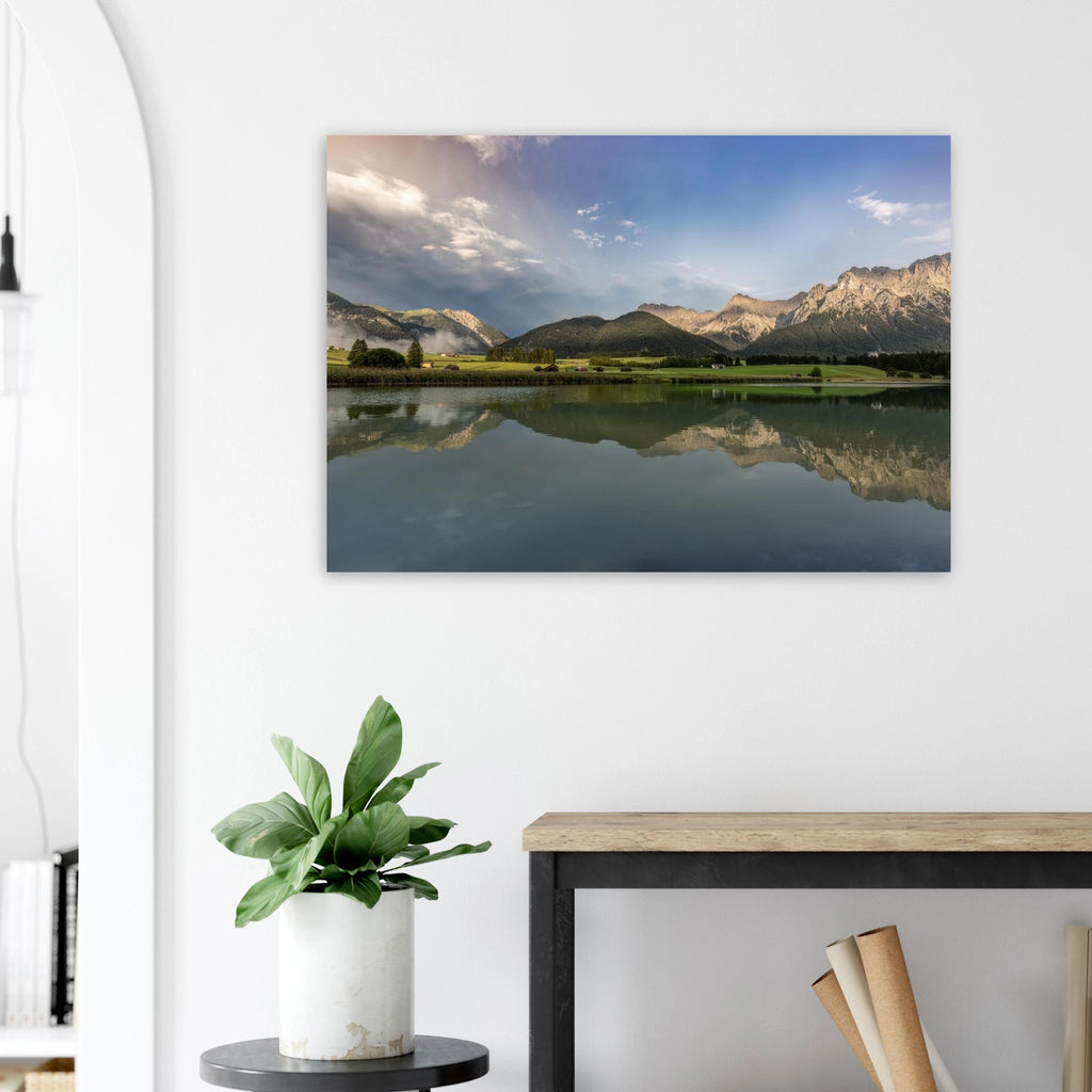
Horizontales, ungerahmtes Poster mit Landschaftsmotiv: ruhiger Bergsee mit klarer Spiegelung, grüne Wiesen, kleine Hütten und das Karwendelgebirge im warmen Licht der goldenen Stunde unter einem dramatischen Himmel.
