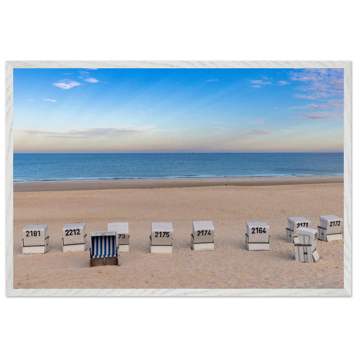 Horizontaler Kunstdruck mit Blick auf den Strand von Westerland auf Sylt: weiße Strandkörbe im hellen Sand, dahinter die ruhige blaue Nordsee und ein weiter sommerlicher Himmel mit feinen Wolken.
