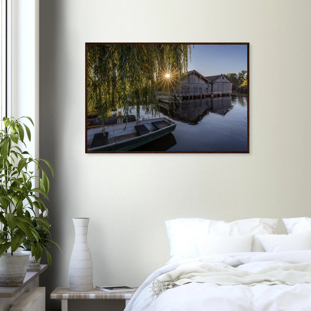  
Gerahmtes Premium-Matt-Poster mit Bootshäusern in Seehausen am Staffelsee bei warmer Morgensonne, eingefasst in einen dunkelbraunen Holzrahmen.