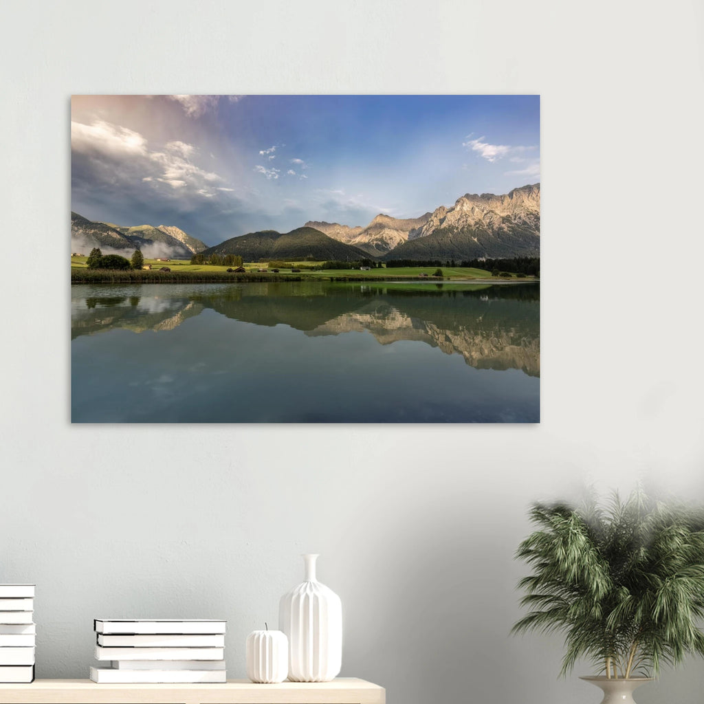 
Horizontales, ungerahmtes Poster mit Landschaftsmotiv: ruhiger Bergsee mit klarer Spiegelung, grüne Wiesen, kleine Hütten und das Karwendelgebirge im warmen Licht der goldenen Stunde unter einem dramatischen Himmel.
