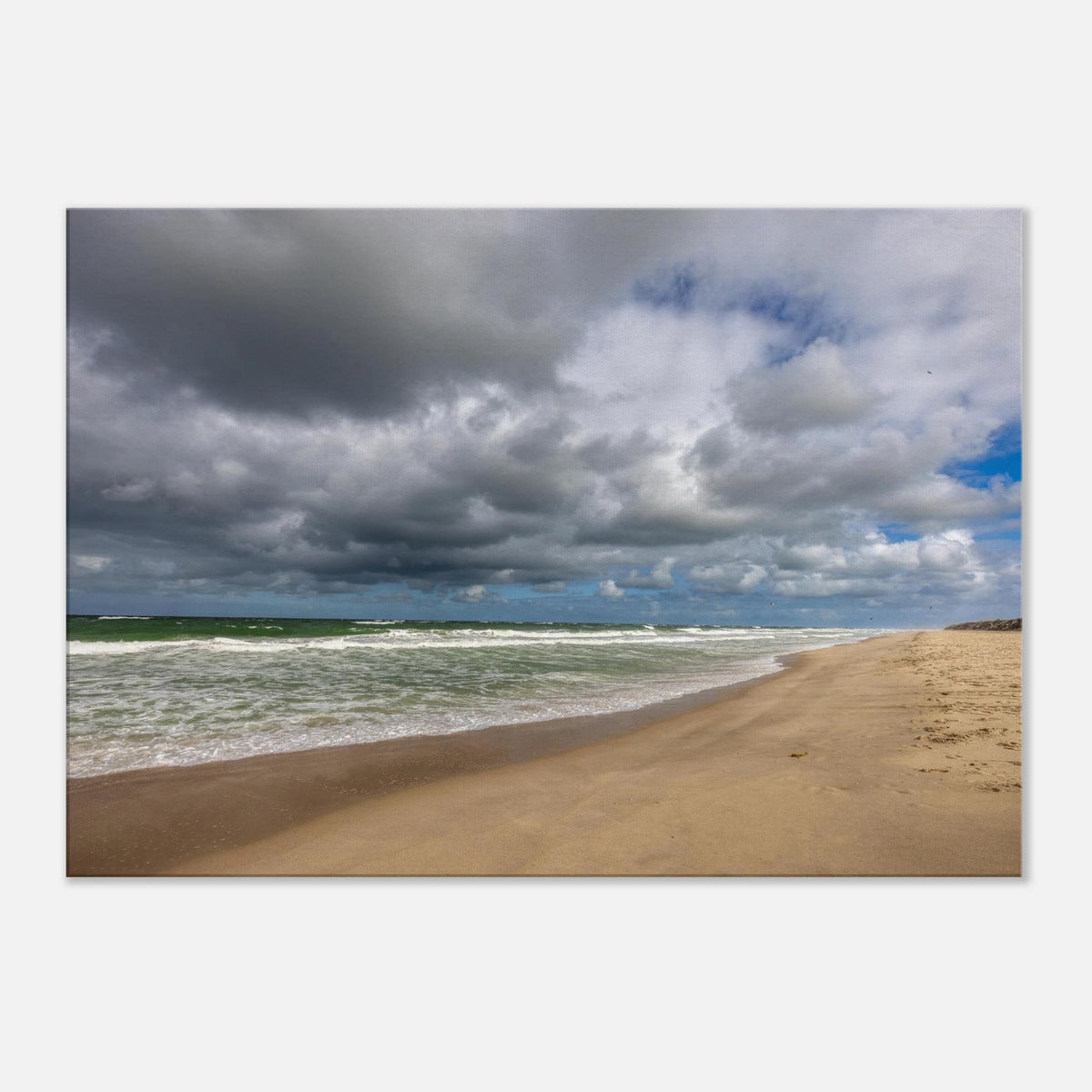 Alttext:
Weite Strandlandschaft in Westerland auf Sylt mit kräftiger Nordseebrandung, aufgewühltem grünblauem Meer, feinem Sandstrand und eindrucksvollen dunklen Wolken unter aufbrechendem blauem Himmel.

