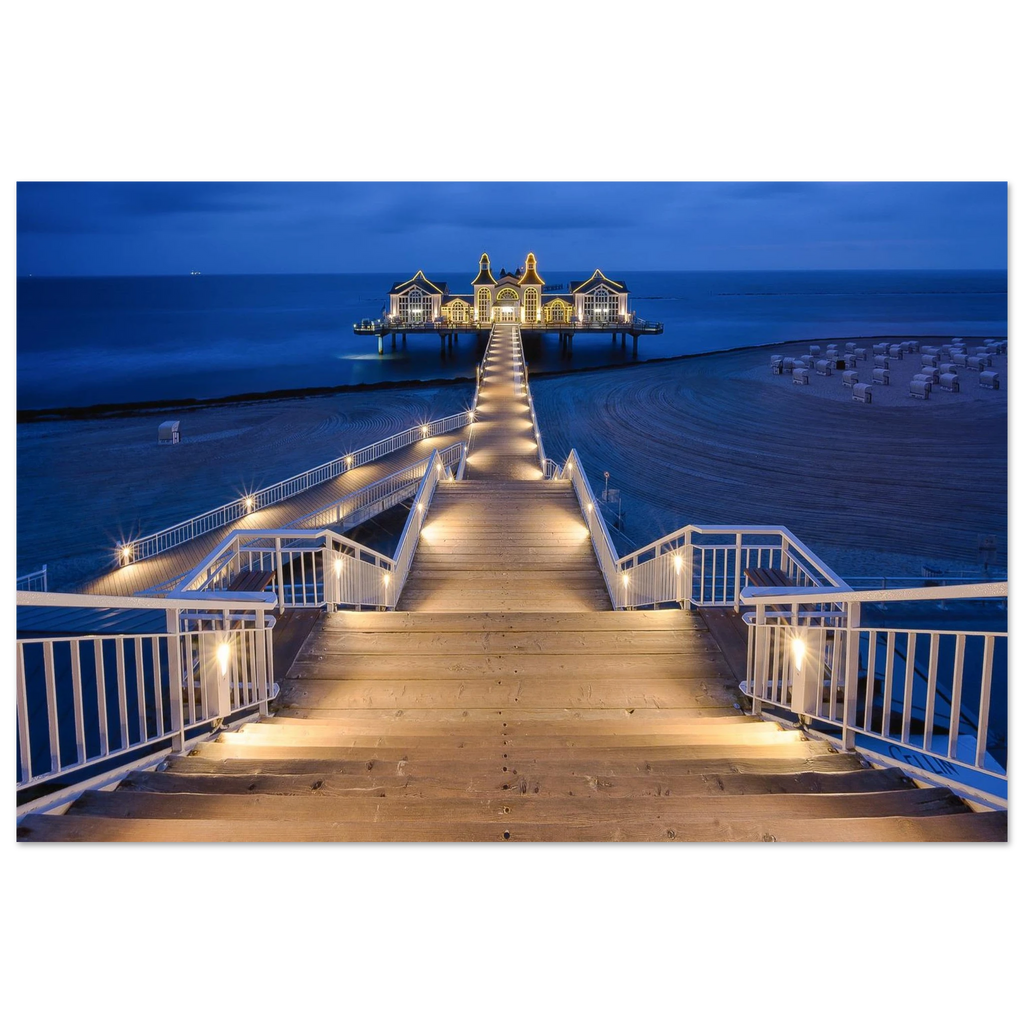 Seebrücke Sellin auf Rügen in der Blauen Stunde am Morgen. Der beleuchtete Holzsteg führt über den ruhigen Strand zur historischen Seebrücke und schafft eine stimmungsvolle Kulisse an der Ostsee.