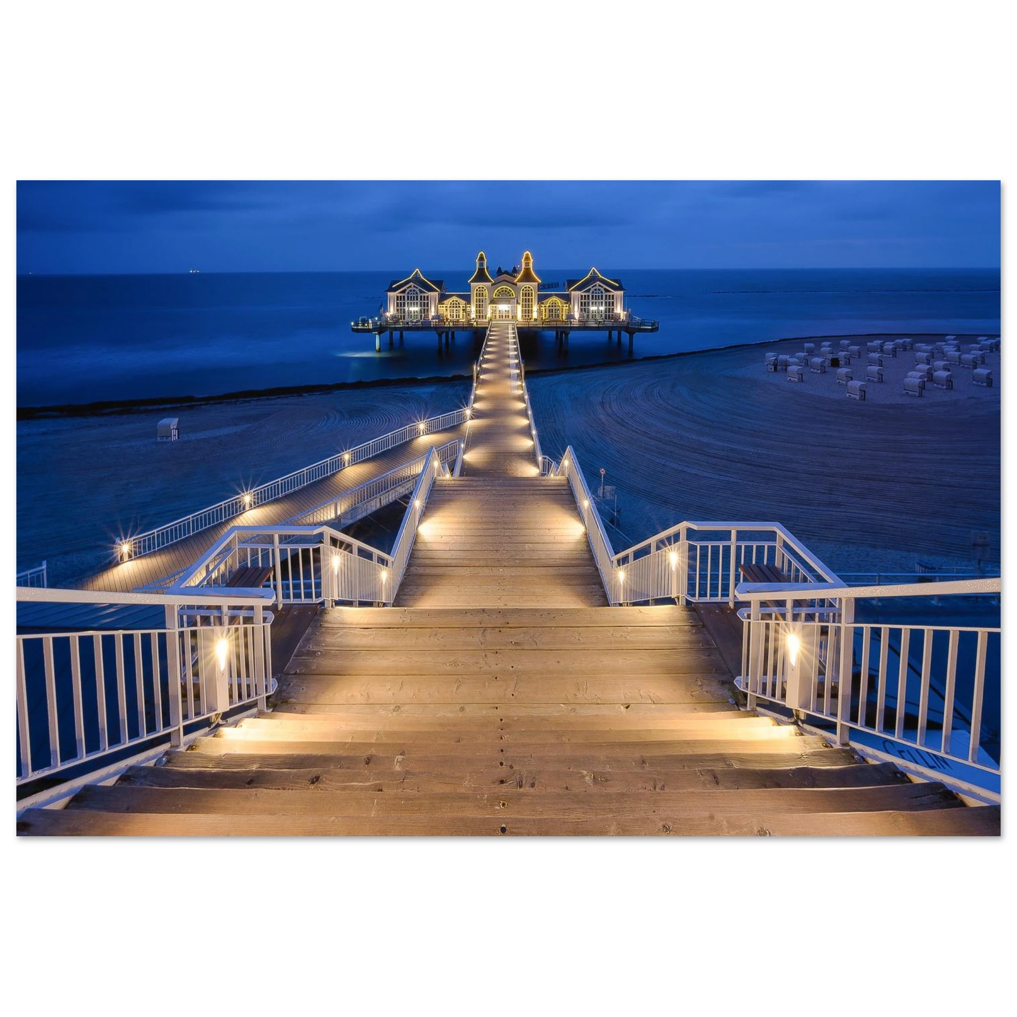 Seebrücke Sellin auf Rügen in der Blauen Stunde am Morgen. Der beleuchtete Holzsteg führt über den ruhigen Strand zur historischen Seebrücke und schafft eine stimmungsvolle Kulisse an der Ostsee.