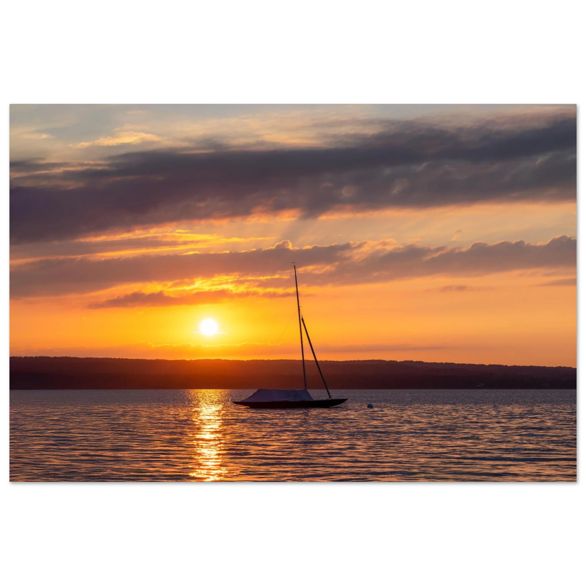 Premium Matt Poster „Ammersee Sonnenuntergang“ von Christina Bauer Photos. Ein einzelnes Segelboot liegt ruhig auf dem Wasser des Ammersees, während die untergehende Sonne den Himmel in warme Orange-, Gold- und sanfte Violetttöne taucht. Das Licht spiegelt sich auf der Wasseroberfläche und schafft eine ruhige, stimmungsvolle Atmosphäre voller Weite, Sommergefühl und natürlicher Eleganz.

