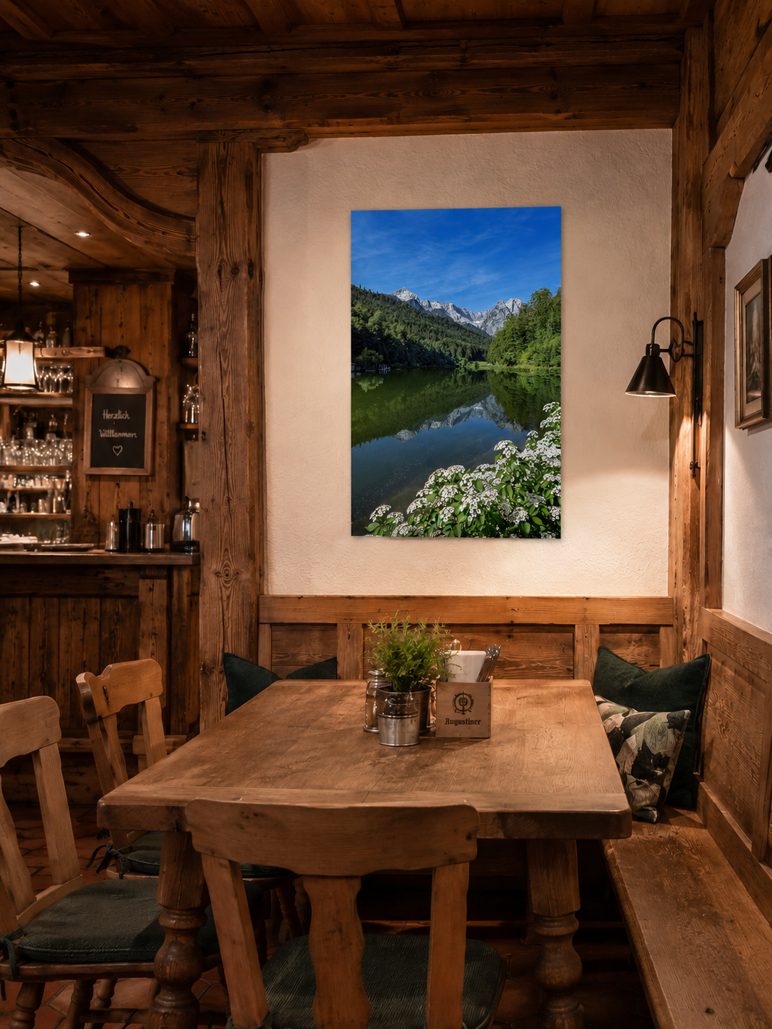 Gemütliche bayerische Gaststube mit viel naturbelassenem Holz, rustikalen Holztischen und Sitzbänken. An der hellen Wand hängt ein vertikales Poster im Format 40 x 60 cm mit einer sommerlichen Ansicht des Riessersees bei Garmisch-Partenkirchen. Die Berggipfel spiegeln sich im ruhigen Wasser, während weiße Blüten das Ufer schmücken. Die warme Beleuchtung und die traditionelle Einrichtung schaffen eine einladende, urige Atmosphäre.