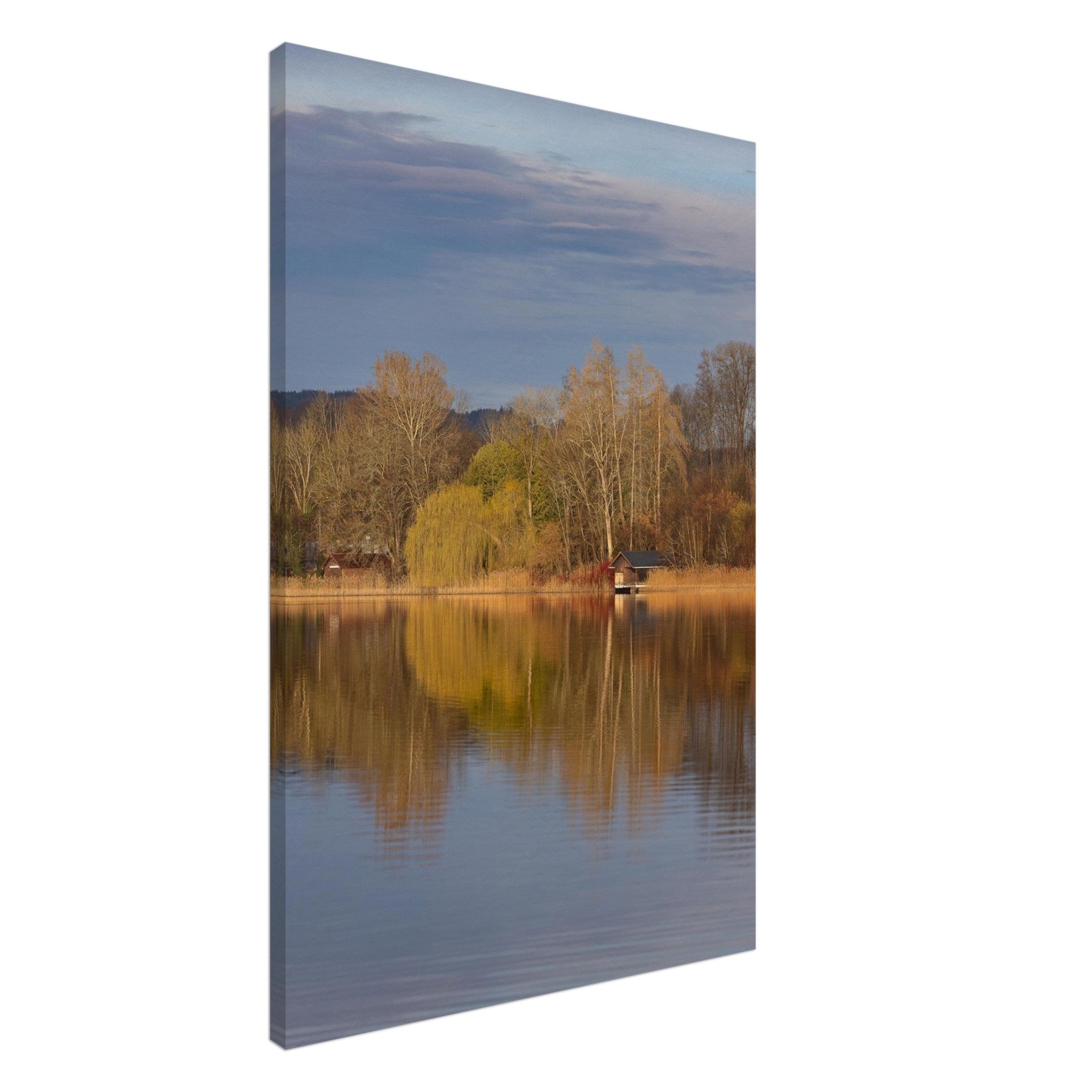 Vertikales Leinwandbild mit einer ruhigen Herbstszene am Staffelsee. Goldene Ufervegetation, eine kleine Bootshütte und kahle Bäume spiegeln sich im stillen Wasser. Warme Herbstfarben treffen auf einen sanft bewölkten Himmel und verleihen dem Motiv eine harmonische, entspannte Atmosphäre. Ungeahmtes Leinwandbild mit natürlicher Ausstrahlung und feinen Details.
