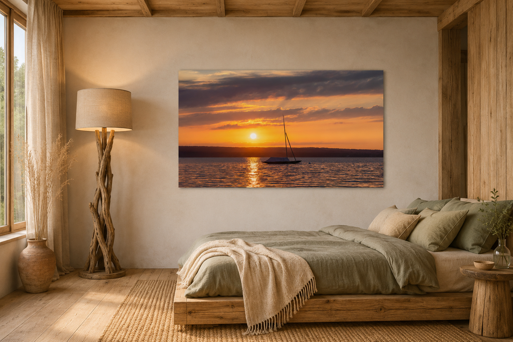 Premium Matt Poster „Ammersee Sonnenuntergang“ von Christina Bauer Photos. Ein einzelnes Segelboot liegt ruhig auf dem Wasser des Ammersees, während die untergehende Sonne den Himmel in warme Orange-, Gold- und sanfte Violetttöne taucht. Das Licht spiegelt sich auf der Wasseroberfläche und schafft eine ruhige, stimmungsvolle Atmosphäre voller Weite, Sommergefühl und natürlicher Eleganz.
