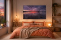 Modernes Schlafzimmer mit warmem, behaglichem Licht und naturbelassenen Holzmöbeln. Über dem Bett hängt ein horizontales Wandbild im Format 40 × 60 cm, das einen beeindruckenden Sonnenuntergang am Staffelsee zeigt. Die Bettwäsche in warmen Apricot- und Orangetönen harmoniert mit den leuchtenden Farben des Himmels im Motiv. Dezente Naturdekoration, weiche Textilien und sanfte Lichtquellen schaffen eine ruhige, einladende Atmosphäre, die zum Entspannen und Wohlfühlen einlädt.