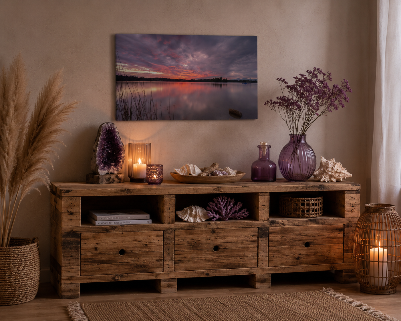 Gemütliche Wohnszene im Naturstil mit einer rustikalen Palettenkommode aus naturbelassenem Holz. Über der Kommode hängt ein kleines, ungerahmtes Leinwandbild im Format 40 × 60 cm mit einer stimmungsvollen Abendaufnahme eines Sees unter dramatischem violett-rosafarbenem Himmel. Die Dekoration greift die Farben des Motivs auf: Violette Glasvasen, getrocknete Blüten, Muscheln, Korallen und sanftes Kerzenlicht schaffen eine harmonische, warme Atmosphäre. Natürliche Materialien und dezente Lichtquellen verleihen