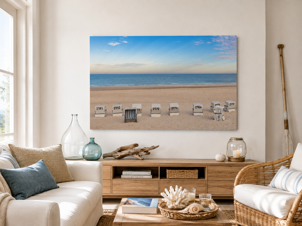 Das Motiv zeigt einen weiten, ruhigen Strand in Westerland auf Sylt in einer klaren, sommerlichen Stimmung. Im Vordergrund liegt der helle, fein strukturierte Sand, in dem mehrere weiße Strandkörbe in einer lockeren Reihe stehen. Einer davon ist geöffnet und mit blau-weiß gestreiftem Innenstoff ein besonderer Blickfang.
Bold mit KI erstellt, Fotografie ohne KI von Christina Bauer
