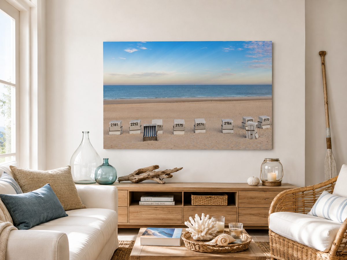Das Motiv zeigt einen weiten, ruhigen Strand in Westerland auf Sylt in einer klaren, sommerlichen Stimmung. Im Vordergrund liegt der helle, fein strukturierte Sand, in dem mehrere weiße Strandkörbe in einer lockeren Reihe stehen. Einer davon ist geöffnet und mit blau-weiß gestreiftem Innenstoff ein besonderer Blickfang.
Bold mit KI erstellt, Fotografie ohne KI von Christina Bauer