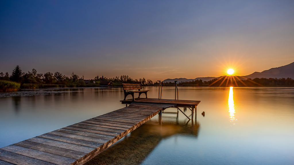 Sonnenaufgang am Kochelsee in Oberbayern an einem Holzsteg 