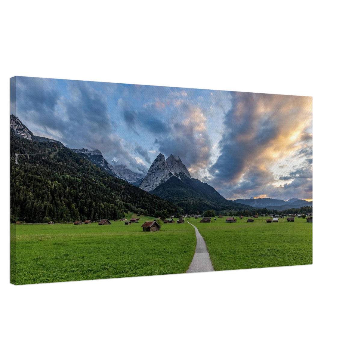 Leinwandbuidl Waxnstoana im Abendliacht, so schee schoo Landschaftsfotografie aus Garmisch-Partenkirchen mit Blick auf das imposante Wettersteingebirge. Ein schmaler Weg führt durch weitläufige grüne Wiesen mit traditionellen Heustadeln. Dramatische Wolken und sanftes Abendlicht tauchen die bayerische Alpenlandschaft in eine stimmungsvolle Atmosphäre.