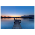 Aluminium-Print mit Sonnenaufgang am Kochelsee: Ruhiger See in sanften Blau- und Orangetönen, ein hölzerner Steg mit Bank führt ins stille Wasser, im Hintergrund Berge und die zarte Morgenstimmung des beginnenden Tages.