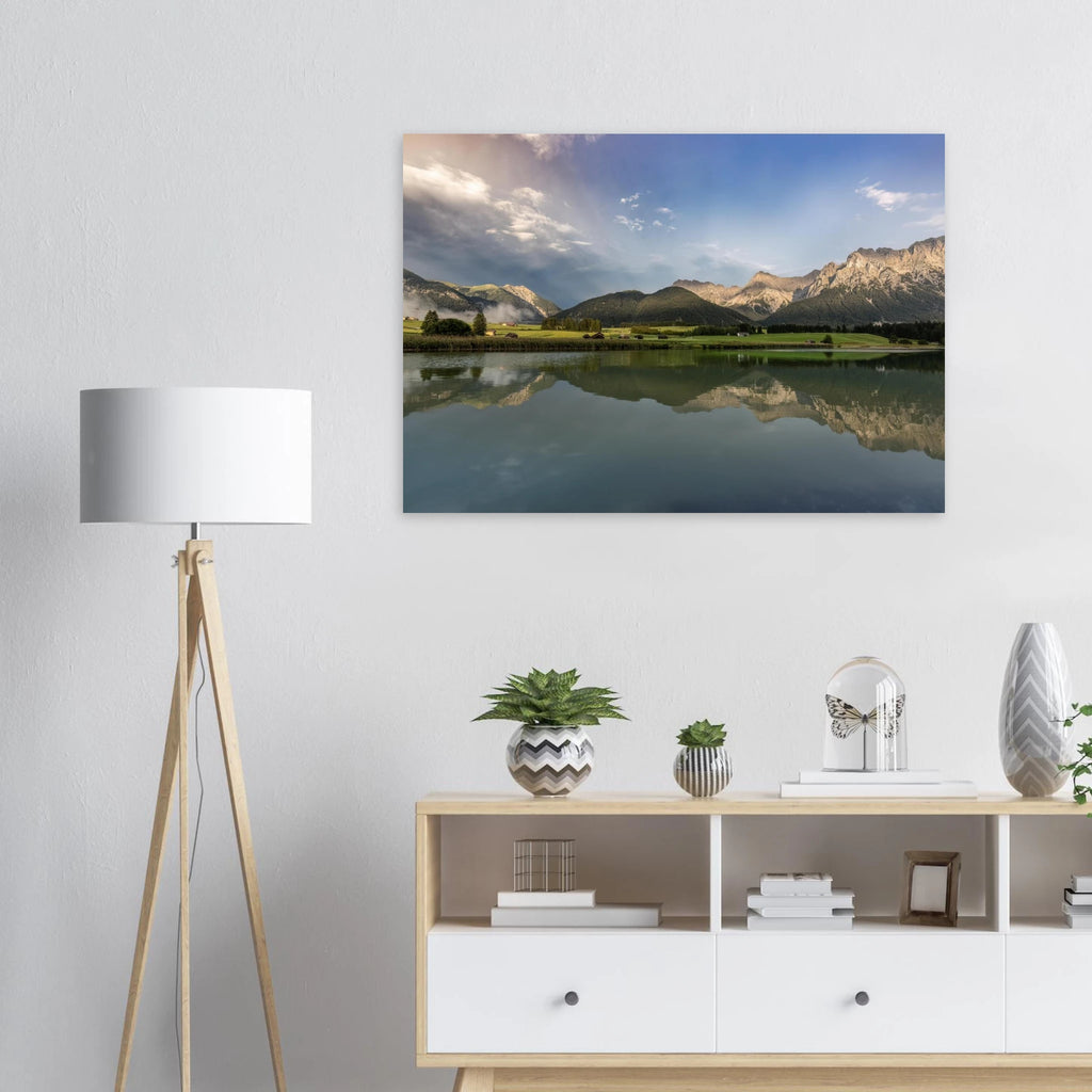 
Horizontales, ungerahmtes Poster mit Landschaftsmotiv: ruhiger Bergsee mit klarer Spiegelung, grüne Wiesen, kleine Hütten und das Karwendelgebirge im warmen Licht der goldenen Stunde unter einem dramatischen Himmel.

