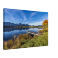 Ein goldener Herbsttag im Allgäu. Der Hopfensee liegt still vor der beeindruckenden Kulisse der Berge, das klare Wasser trägt ihre Spiegelungen und am Ufer leuchtet der Herbst in warmen Farben. Der kleine Holzsteg führt hinaus in diese besondere Ruhe, die man manchmal nur in der Natur findet. Foto auf Leinwand 